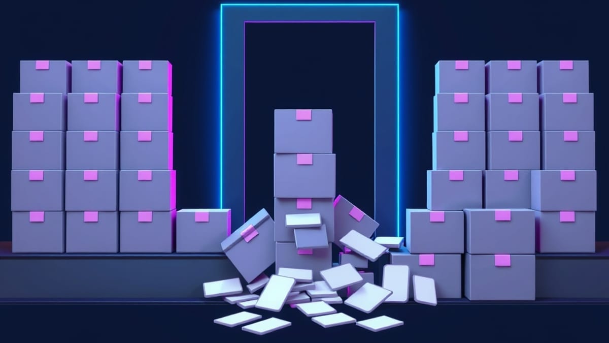 A conveyor belt moves many identical blank grey boxes toward a narrow doorway while a few jam and topple, spilling blank labe