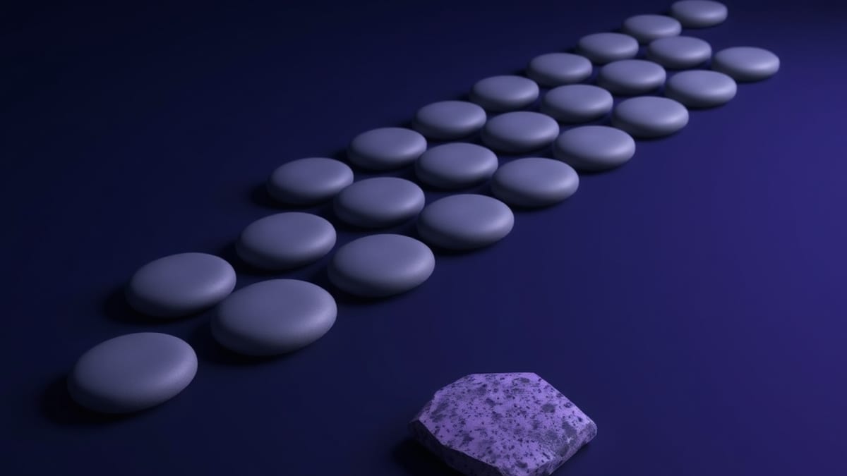 A neat row of identical grey pebbles with one distinct speckled, angular stone resting apart from the line.