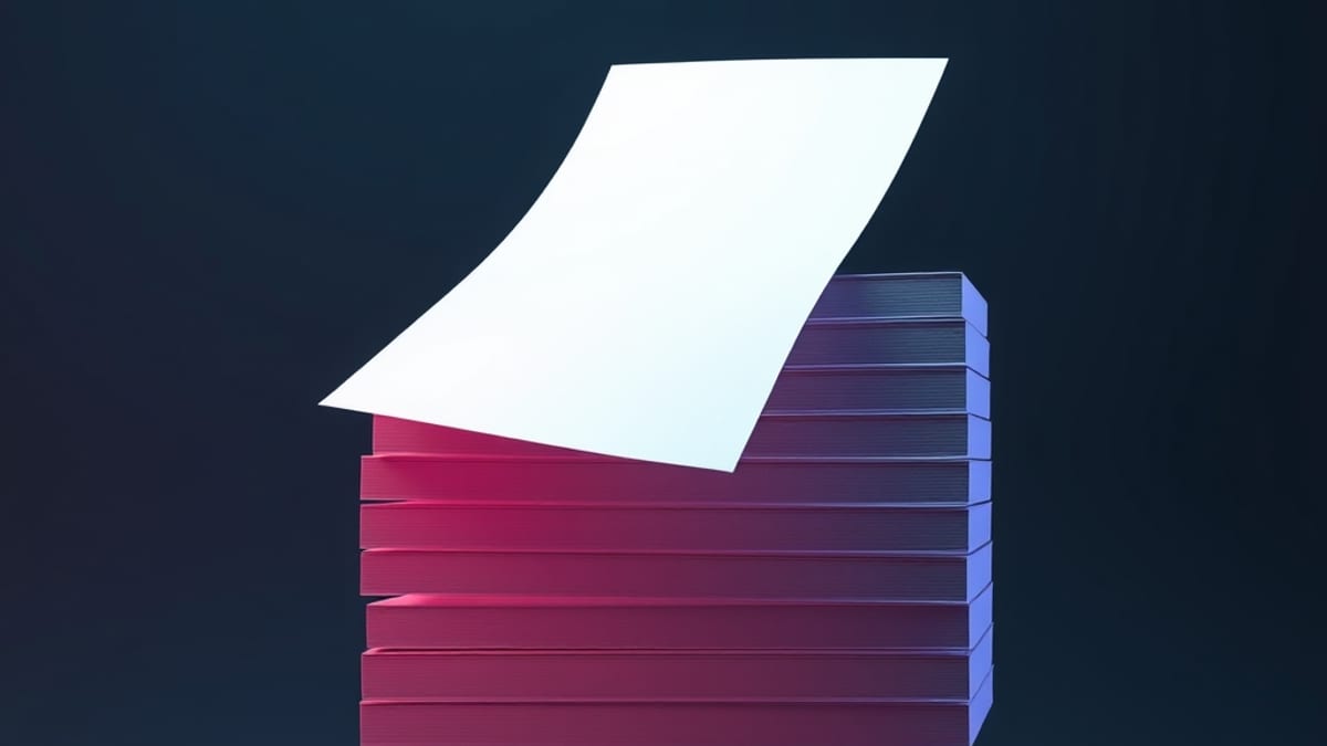 A loose sheet of paper floating free next to a rigid metal frame holding a neat stack of identical sheets.
